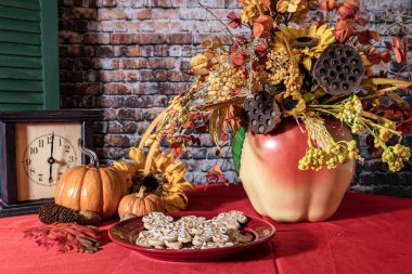gingerbread cookies on red with fall flowers in old cookie jar pumpkins and brick wall background