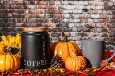 Sonbahar sahnesinde kahve kutuları ve turuncu kabaklı fasulyeler ve yatay tuğla kaplama arka planlı sarı ayçiçeği ve insan yok.