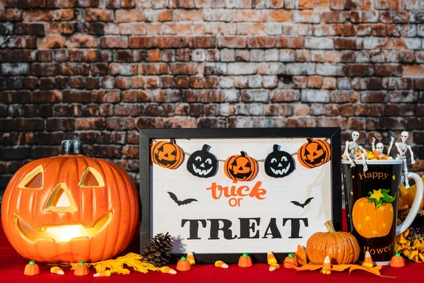horizontal Halloween scene with jack o lantern skeletons and candy corn on red with trick or treat sign and brick wall background