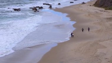 ABD, CALIFORNIA - 29 Kasım 2019: insanlar okyanus boyunca yürür. Malibu bölgesindeki Pasifik Okyanusu 'nun kumlu kıyılarında büyük dalgalar kıyıya vuruyor.