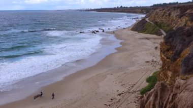 ABD, CALIFORNIA - 29 Kasım 2019: insanlar okyanus boyunca yürür. Malibu bölgesindeki Pasifik Okyanusu 'nun kumlu kıyılarında büyük dalgalar kıyıya vuruyor.