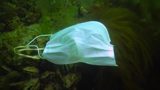 水の下のプラスチック Covid 19パンデミック後の医療用マスクは海で泳ぐ 環境汚染 流行病検疫終了後に医療マスクを放り出す — ストック動画