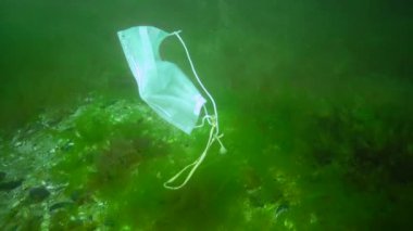 Suyun altındaki plastik. Covid-19 salgınından sonra okyanusta yüzen bir tıbbi maske. Çevre kirliliği. İnsanlar Salgın Karantina Sonrası Tıbbi Maske Atmışlar.