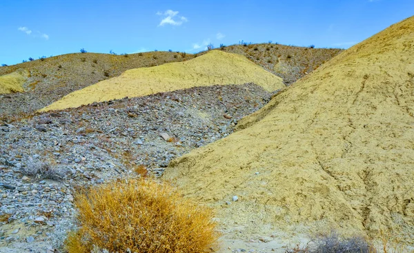 Hills in the California desert from various colored clay formations. Desert vegetation around