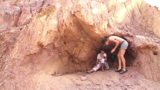 Dos mujeres se esconden del sol a la sombra de las rocas — Vídeo de stock