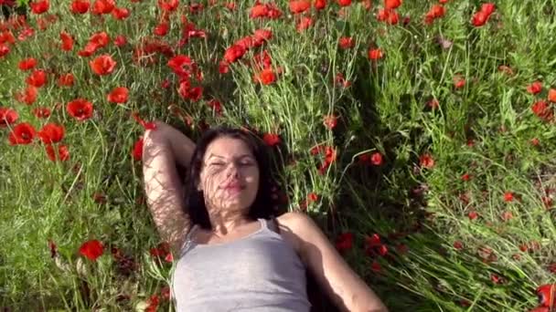 Mädchen lehnt sich zwischen den Mohnblumen zurück — Stockvideo