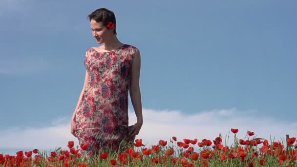 짧은 머리를 가진 여성 모델은 천천히 꽃 들 사이에서 산책 — 비디오