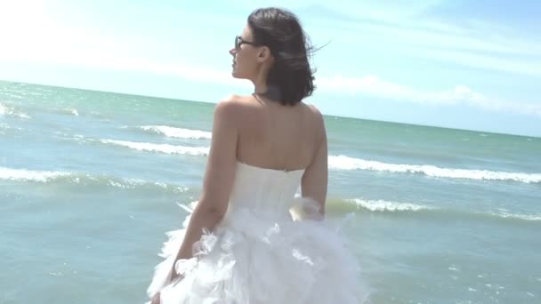 Κορίτσι σε ένα κομψό γαμήλιο φόρεμα που στέκεται στην παραλία — Αρχείο Βίντεο