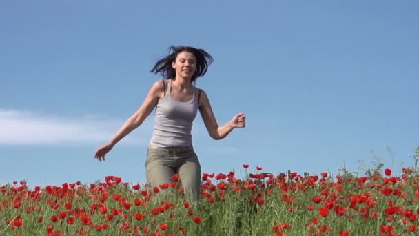 Beautiful brunette is running on the field of poppies — Stock Video