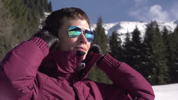 Urlaub in den Bergen. junge Frau trägt eine Kapuze vor dem Hintergrund einer winterlichen Berglandschaft — Stockvideo
