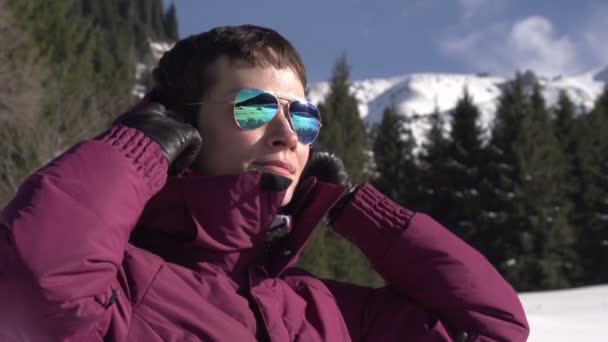 Vacaciones en las Montañas. Mujer joven lleva una capucha sobre un fondo de un paisaje de montaña de invierno — Vídeo de stock