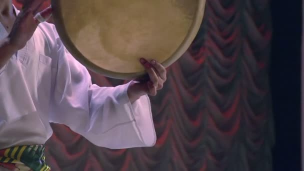 Мужчина в национальной одежде держит азиатский барабан . — стоковое видео