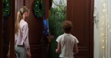 Çocuklar Kurye ile Noel Ağacı Tanışır. Bir kurye eve büyük ambalajlı bir Noel ağacı getirir. O, çocuklar tarafından karşılanır. Kız tabletin üzerine imza atıyor. Kurye çocuğa Noel ağacı süsü verir.