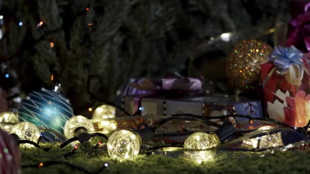 クリスマスの夜カメラは 輝く弓 クリスマスツリーの装飾や輝くガーランドで飾られたさまざまなギフトボックスに沿ってゆっくりと移動します — ストック動画