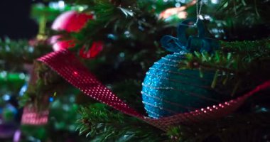 Parlak parlak çelenklerle süslenmiş Noel ağacı dalları ve Noel süslemeleri kameranın önünde yavaşça hareket ediyor