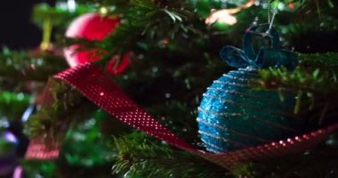 Parlak Noel Oyuncakları. Parlak parlak çelenklerle süslenmiş Noel ağacı dalları ve Noel süslemeleri kameranın önünde yavaşça hareket ediyor