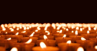 Bitmek bilmeyen yanan mumlar. Kamera, siyah arka planda yanan mumlarla dolu büyük bir açıklığın üzerinde yavaşça hareket eder. Hava akımından ışıklar titriyor.