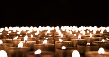 Yanan Mumlar 'dan Horizon' a. Birçok küçük yanan mum mutlak karanlıkta ufukta ateşli bir halı oluşturur. Rüzgar mumları üflüyor.