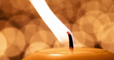 Candle Wick 'te Dans Ateşi. Büyük bir mumun yanan fitili bulanık ışıkların arka planına yakın. 120fps hızla çekilmiştir.