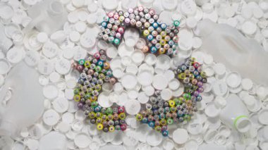 Plastik Geri Dönüşüm Çağrısı Konsepti. Döngü. Geri dönüşüm ve Geri Dönüşüm Sembolü eski AA pillerden oluşur. Beyaz plastik şişeler ve kapaklar arasında yavaşça döner.