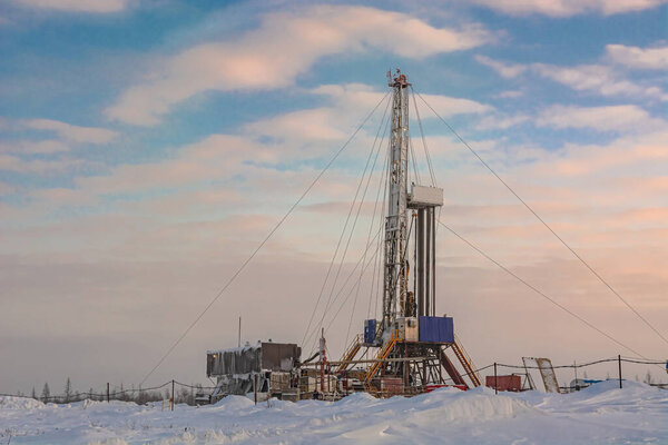 Drilling wells in the winter at an oil and gas field in the Arctic. Polar day with textured beautiful sky. Steam puffs for heating equipment