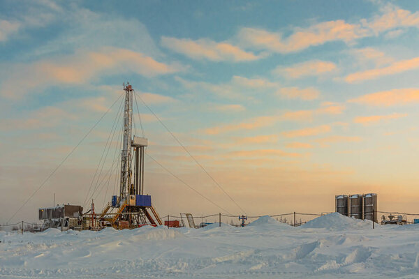 Drilling wells in the winter at an oil and gas field in the Arctic. Polar day with textured beautiful sky. Steam puffs for heating equipment