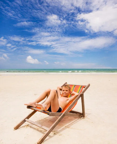 Drôle de garçon dans la chaise de plage sur la plage — Photo