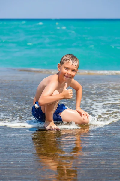 Uśmiechnięty chłopiec na plaży z kciuki — Zdjęcie stockowe
