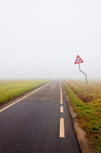 Niebla en camino rural vacío con señal de peligro —  Fotos de Stock