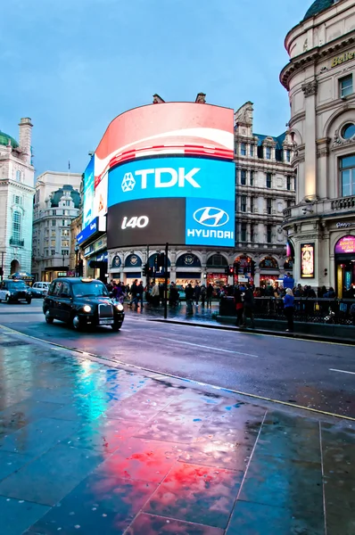 Piccadilly Circus sinalização de néon refletida na rua com taxia — Fotografia de Stock