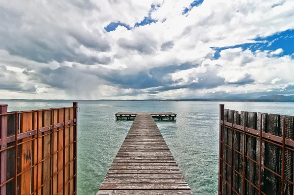 Molo con cielo drammatico sul lago di Garda - Italia — Foto Stock