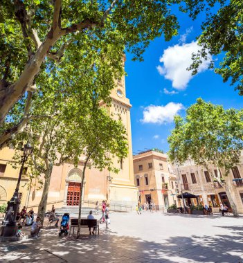Barselona, İspanya - 7 Temmuz 2017: Placa de la Concordia ve Santa Maria del Remei kilisesinin Barcelona, İspanya 'daki banklarda yerel halk ile gündüz görünümü. Les Corts, 20. yüzyılın başlarına kadar Barselona 'dan bağımsız bir kasabaydı.