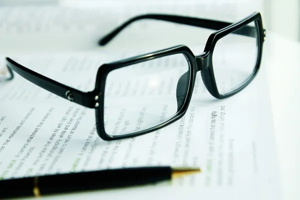 Glasses and a pen on a book Royalty Free Stock Images