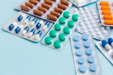 Farklı tabletler, haplar, kapsül ilaçları mavi arka planda su toplayan paketler. Tedavi kavramı, tıp. Seçici odak.
