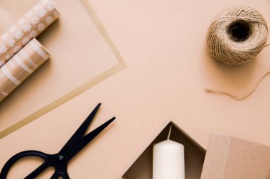 Noel hediyesi paketleme konsepti. Kahverengi kağıt, ip, bant ve makas bej arka planda, üst manzara. El yapımı. Düz yatıyordu. Boşluğu kopyala.