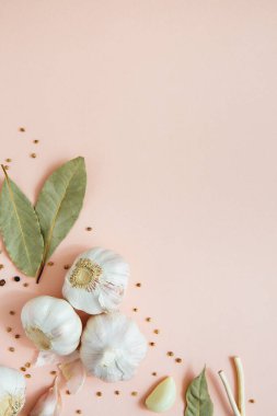 Baharatlı, biberli ve defne yapraklı pembe arka planda sarımsak. Baharatlar ve baharatlar. Yemek arkaplanı. Uzayı kopyala Seçici odak.