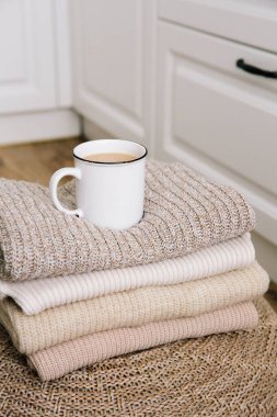 Bir fincan sıcak kahve ve sütlü örgü giysiler. Sonbahar havası. Ev konforu, rahat bir ortam ve kış sabahı. Hygge. Dikey fotoğraf.