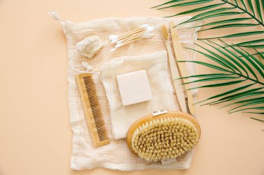 Doğal banyo aksesuarları: bambu diş fırçaları, bambu kulak çubukları, organik sabun, bej arka planda yeniden kullanılabilir pamuk torbaları. Sıfır atık alışveriş, çevre dostu yaşam tarzı, plastiksiz.