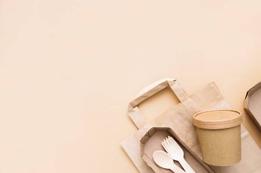 Sıfır atık, çevre dostu, tek kullanımlık, karton, bej arka planda kağıt kaplar. Yukarıdan bak. Eko el işi kağıt sofra takımı.