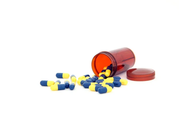 Isolated capsules spilling out from small bottle — Stock Photo, Image