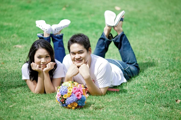 Jeune couple couché sur l'herbe ensemble — Photo