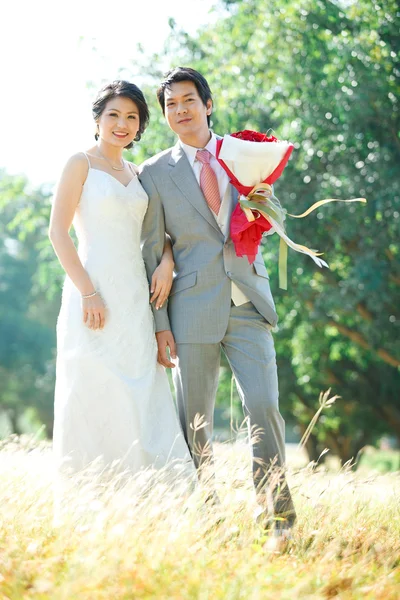 Пары жениха и невесты, стоящие над полем лугов — стоковое фото