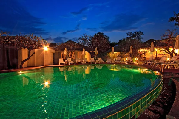 Sedie a sdraio e ombrellone circondano una piscina — Foto Stock