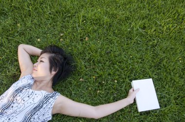 Genç bir kadın tarlada kitap okuyor.