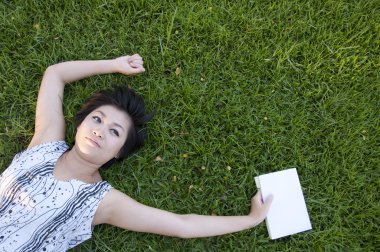 Genç bir kadın tarlada kitap okuyor.