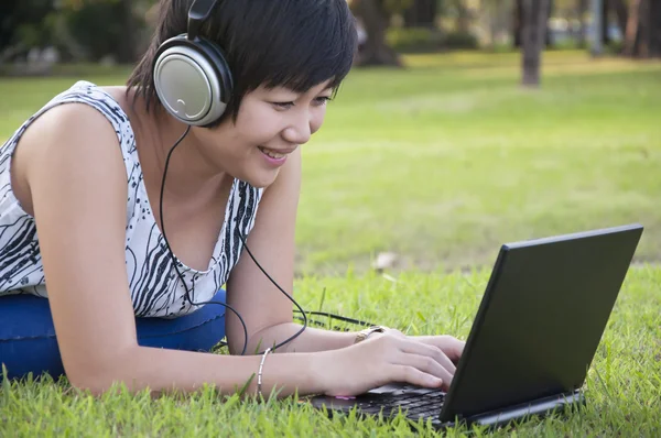 Beautiful asian woman listening music in the park — Stock Photo, Image