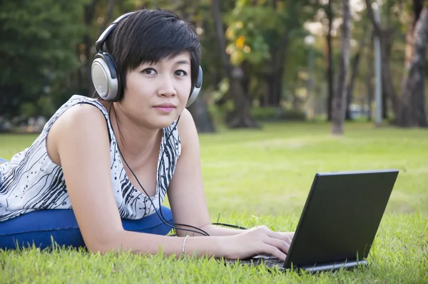 Krásné asijské ženy poslech hudby v parku — Stock fotografie