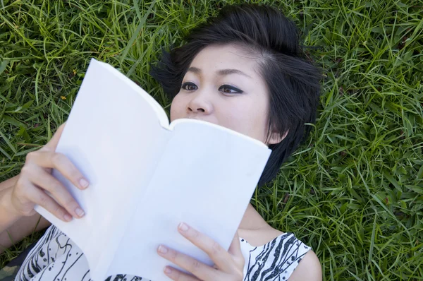 Jovem mulher lendo um livro no campo — Fotografia de Stock