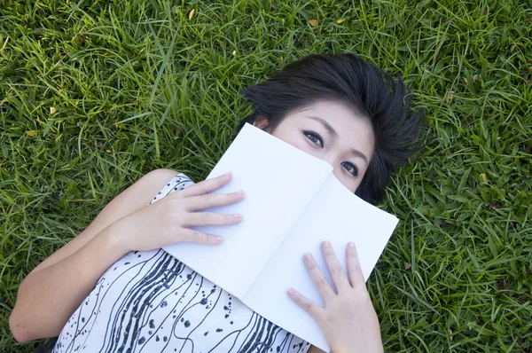 Genç bir kadın tarlada kitap okuyor. — Stok fotoğraf