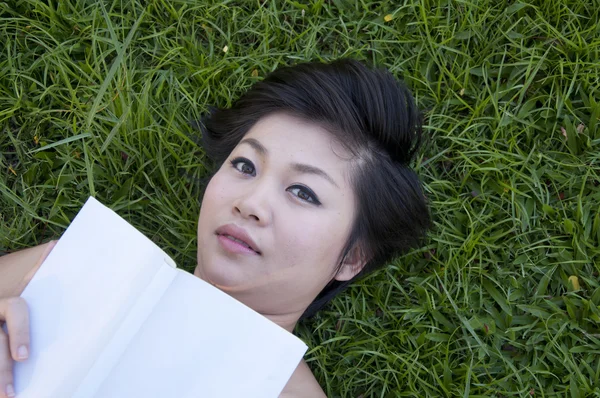 Jovem mulher lendo um livro no campo — Fotografia de Stock